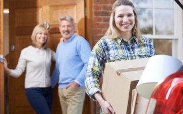 18 years old girl moving out from her parents house holding a box