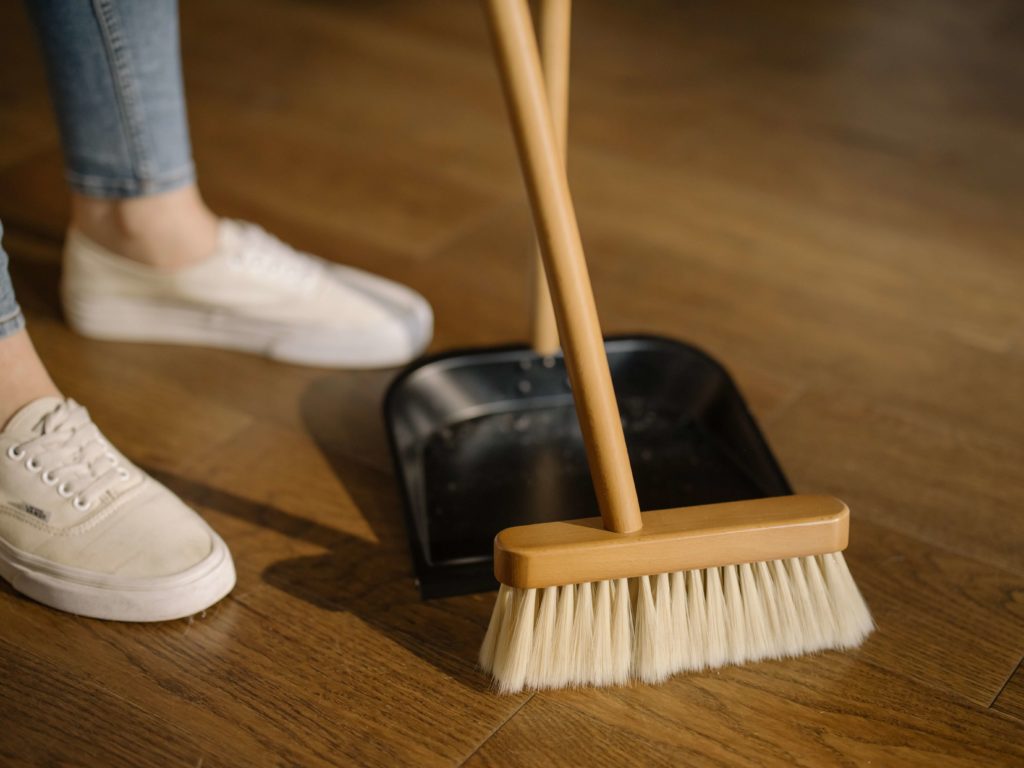  a person using a a broom and a dust pan