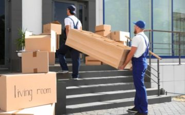 Professional movers moving boxes and a bookshelf