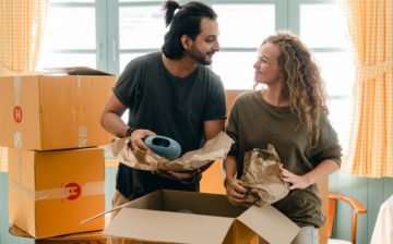a man and a woman packing items into a moving box