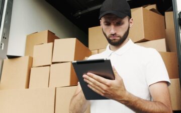 a mover writing inventory list of moving boxes