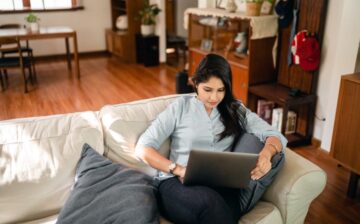 a woman seating on a couch with her laptop
