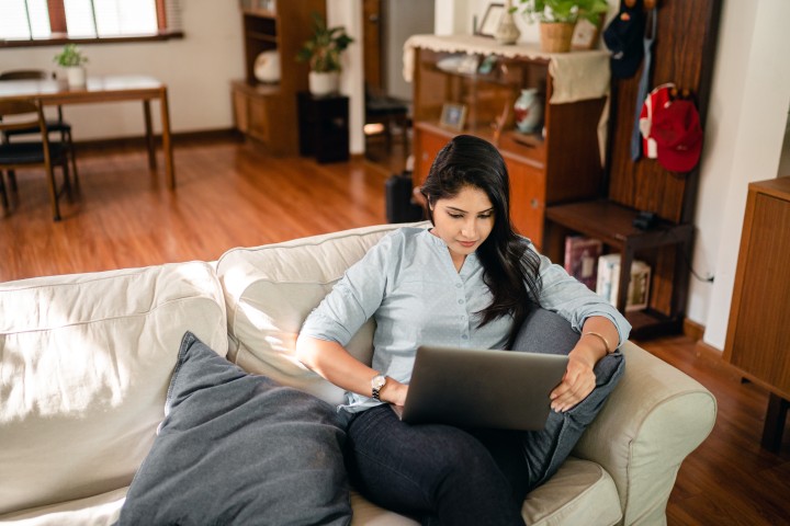 a woman seating on a couch with her laptop