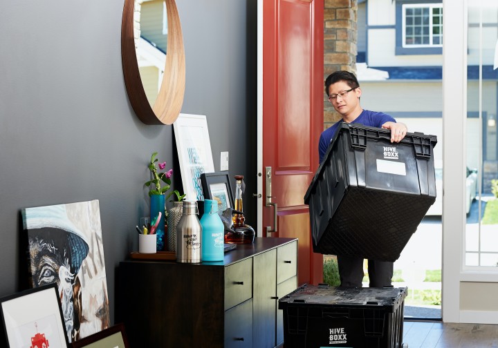 a person is holding a plastic bin entering his home