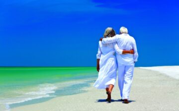 a retired couple is walking the beach