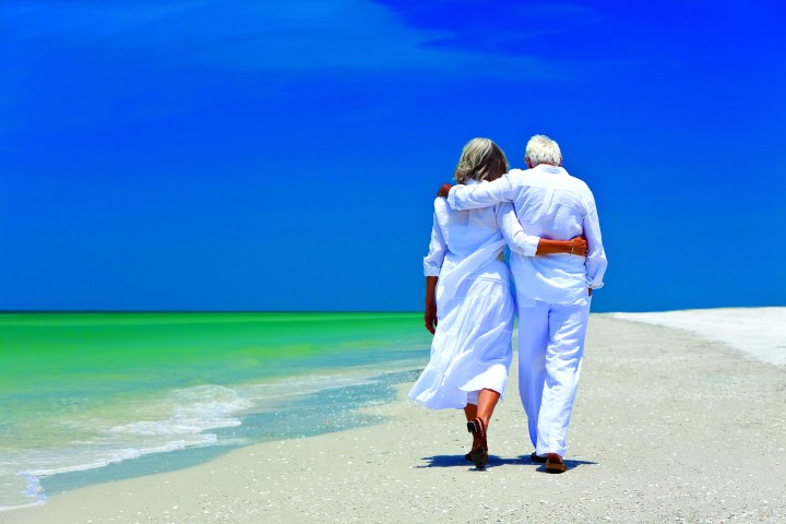 a retired couple is walking the beach
