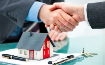 two men shakes hands with papers on a table