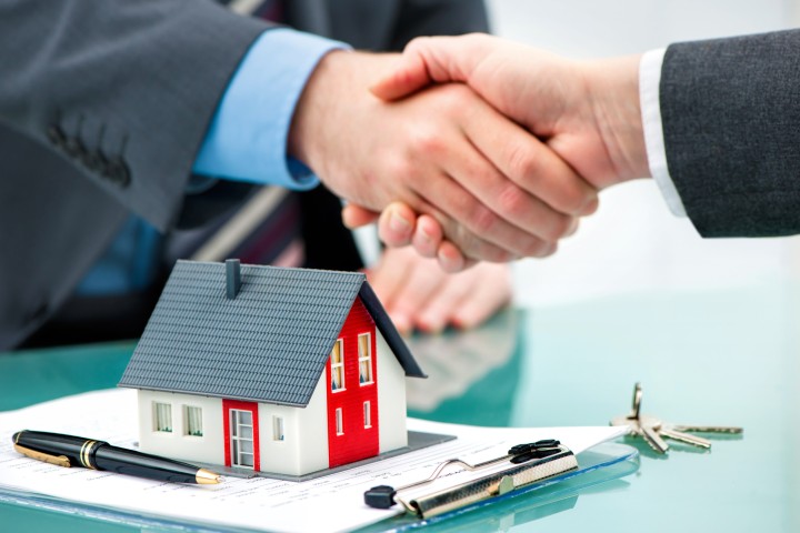 two men shakes hands with papers on a table