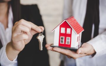 a person holding toy house with its keys