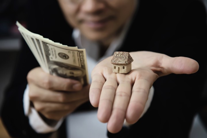 man holding house and money in the other hand