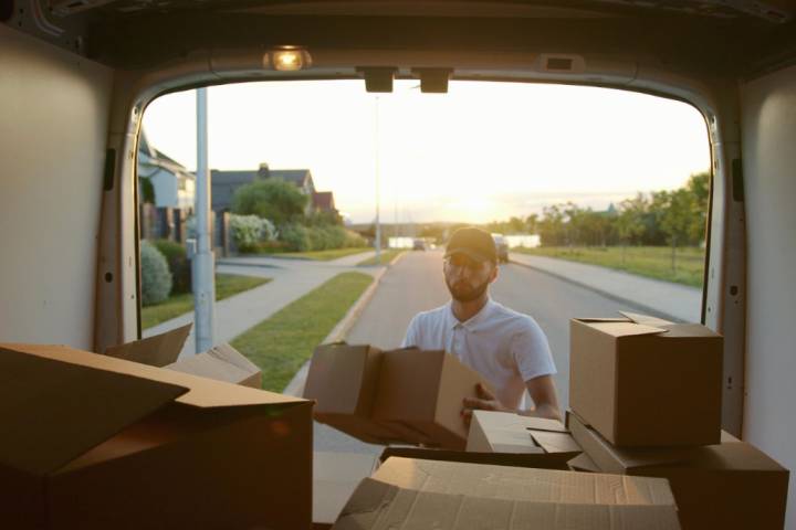 man removing moving boxes from van