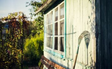 garden rake leaning on white wooden wall