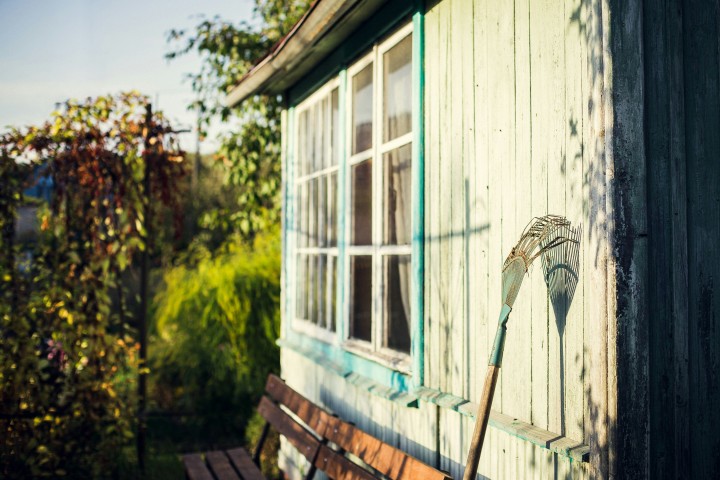 garden rake leaning on white wooden wall