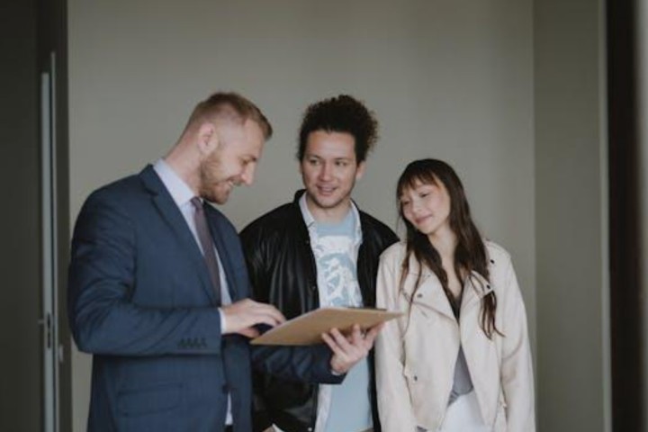 man with computer and a couple standing talking