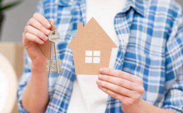 man holding cardboard house and key