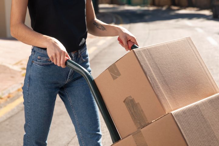 woman with moving dolly and moving boxes